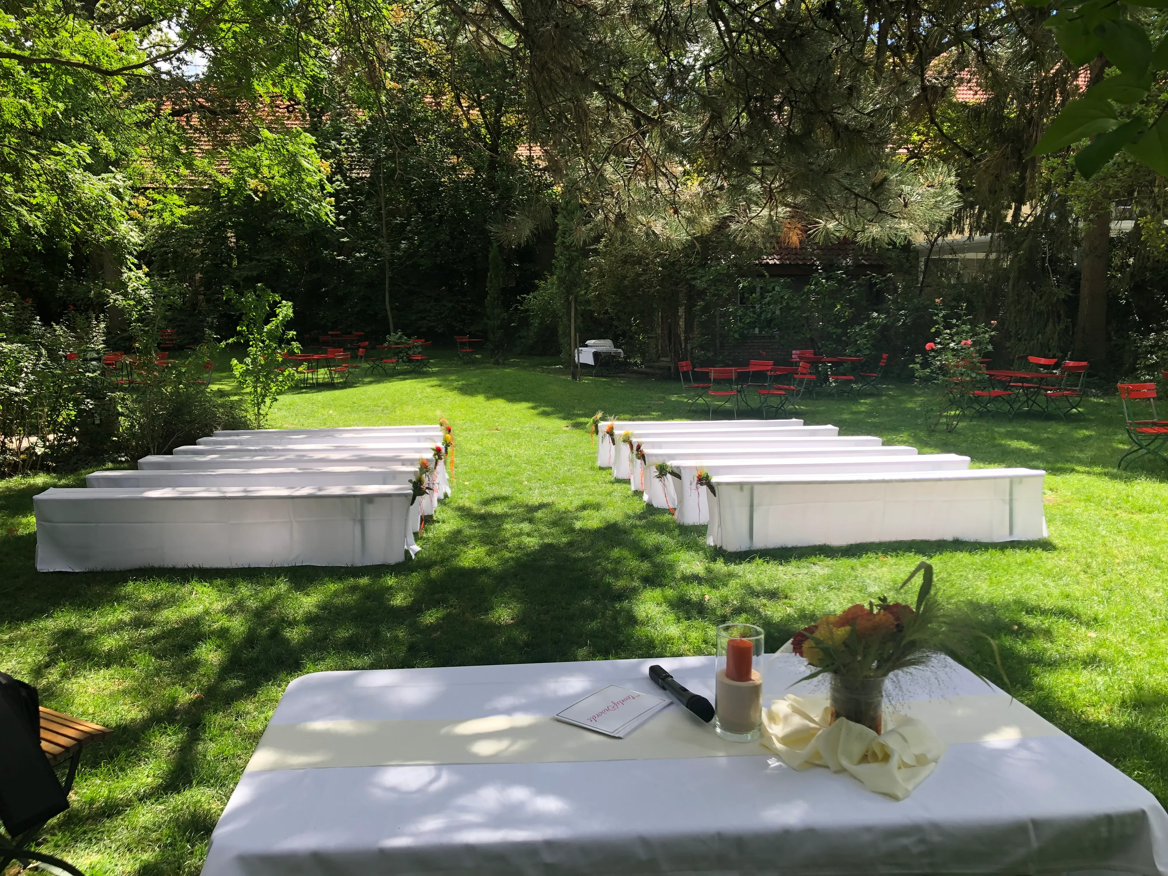 Trauung-Setup im Park des Junghofs mit weißen Sitzbänken und Rednertisch