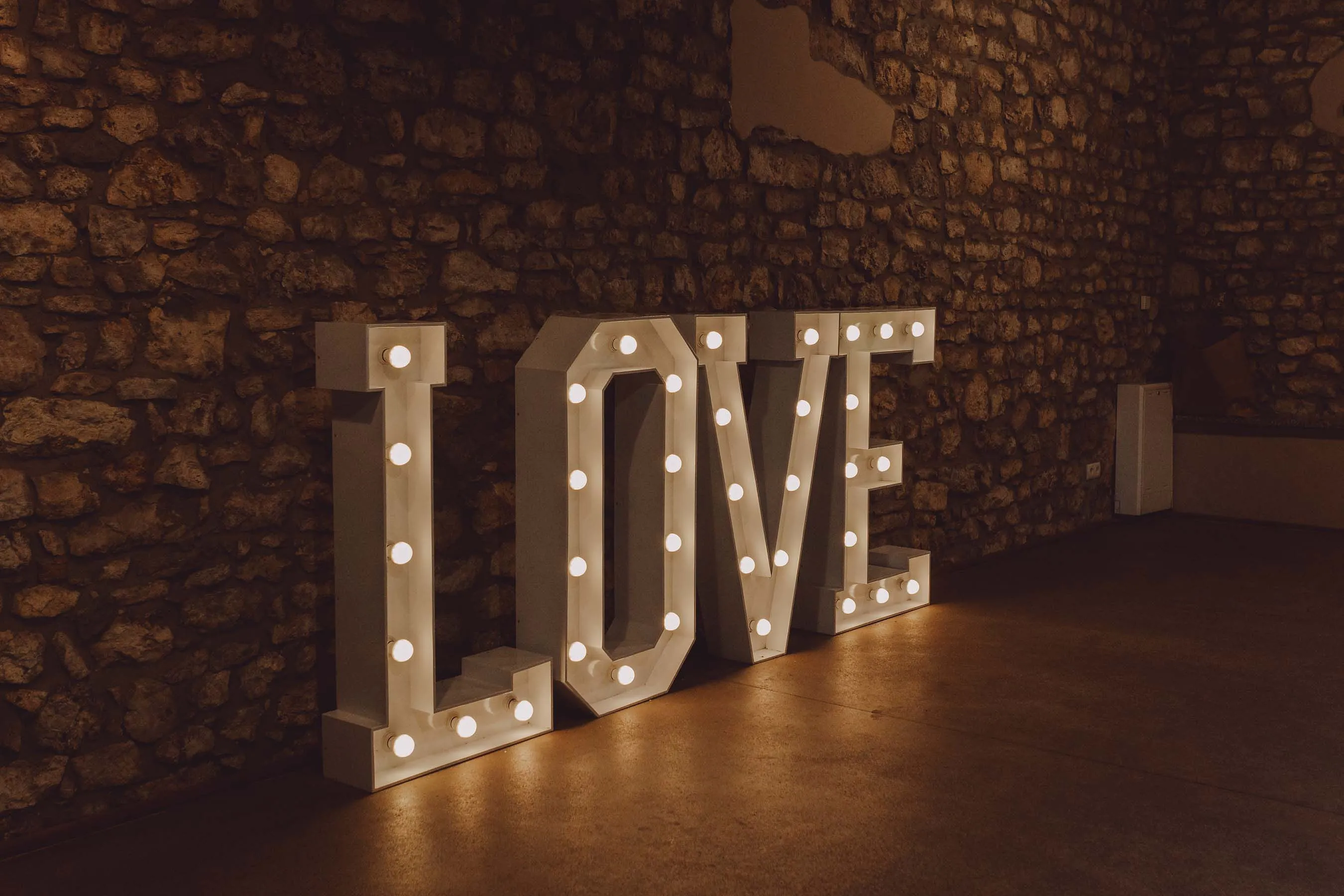 LOVE Leuchtbuchstaben mit warmem Abendlicht vor Natursteinmauer