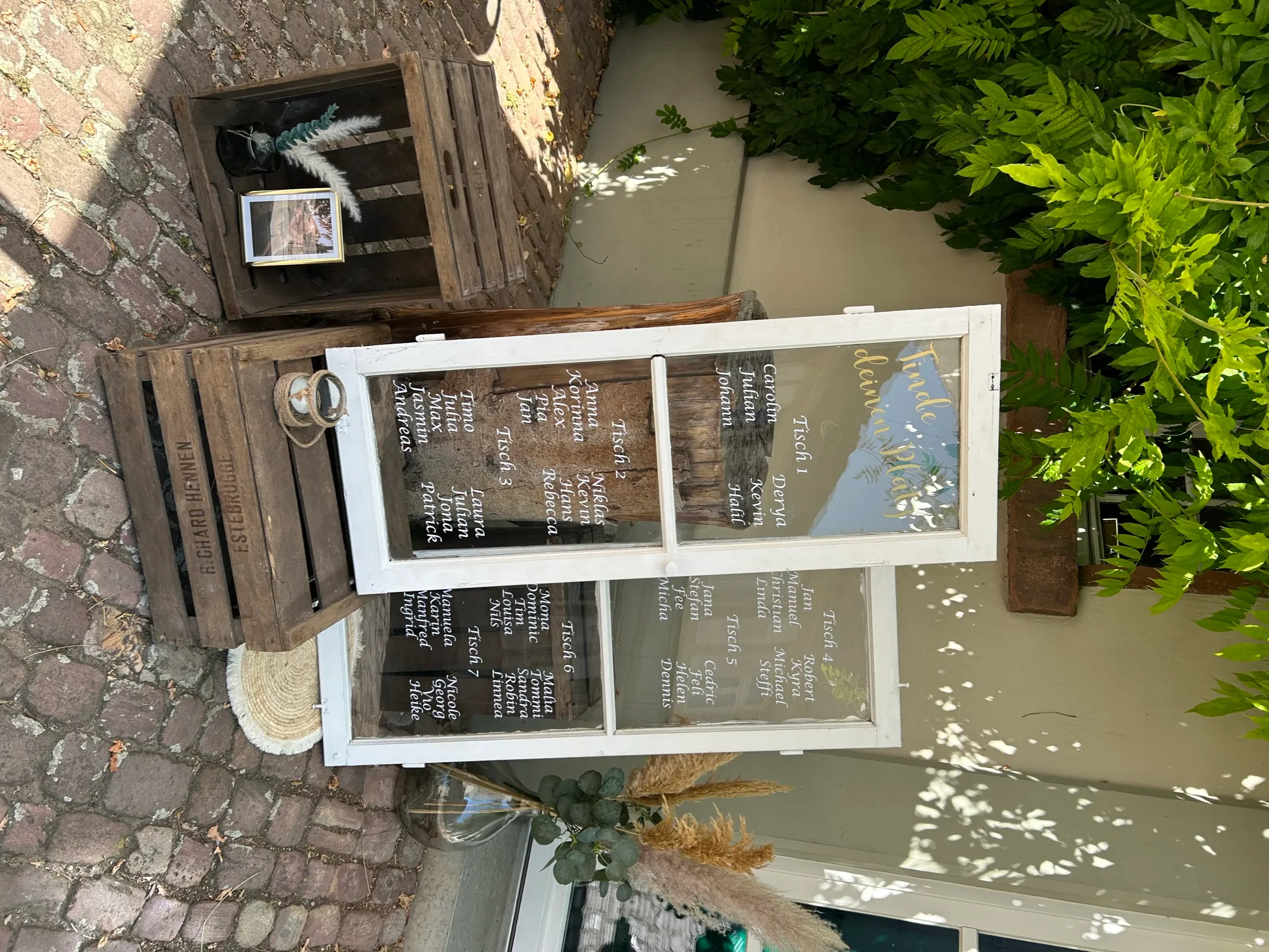 Vintage-Sitzplan aus alten Fensterscheiben mit goldener Schrift auf Holzkisten