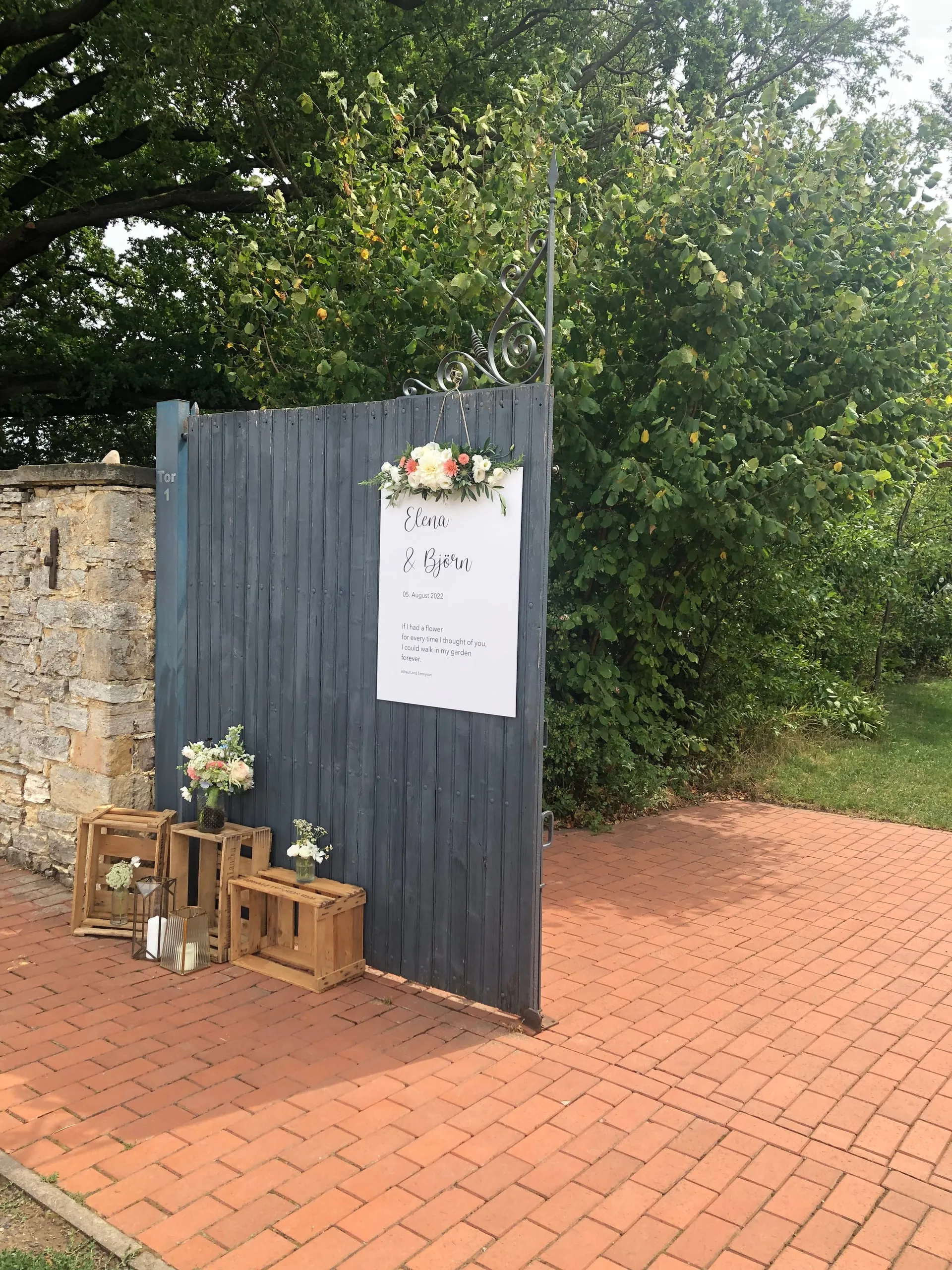 Rustikales Willkommensschild mit Holzkisten und Blumendeko bei einer Hochzeit